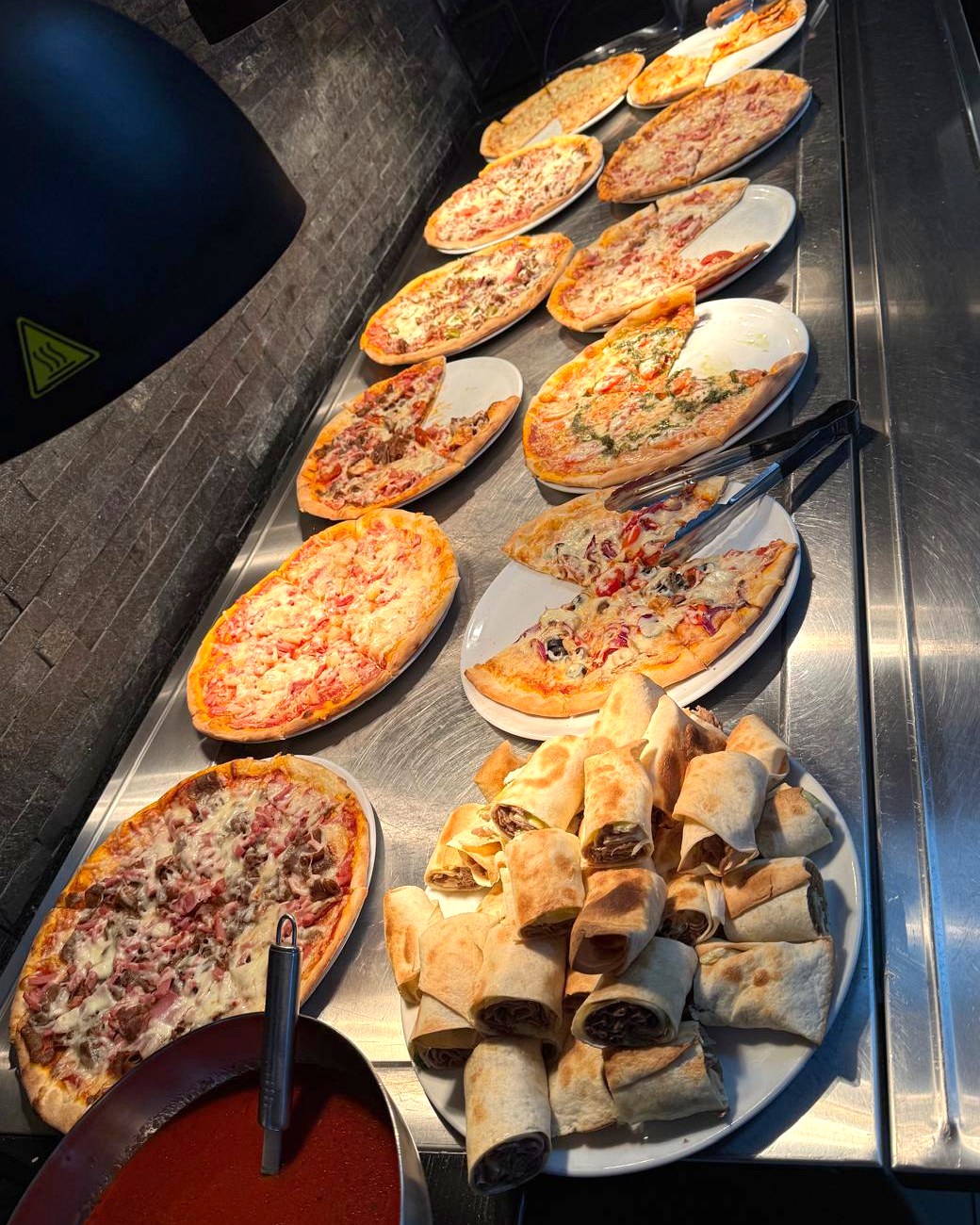 Lämmin ruokapöytä pizzoineen ja liharulloineen La Melin buffetissa